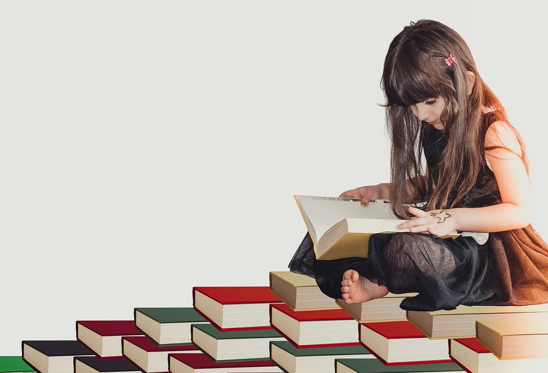 girl on stack of books reading